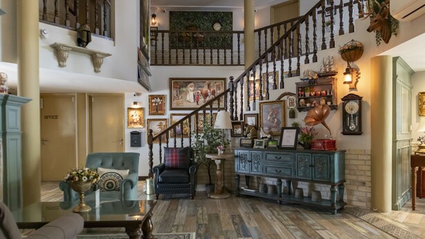 Ein geräumiger Eingangsbereich mit einer imposanten Treppe, einer Sitzecke mit blauem Sessel und einem dekorativen Schrank.
