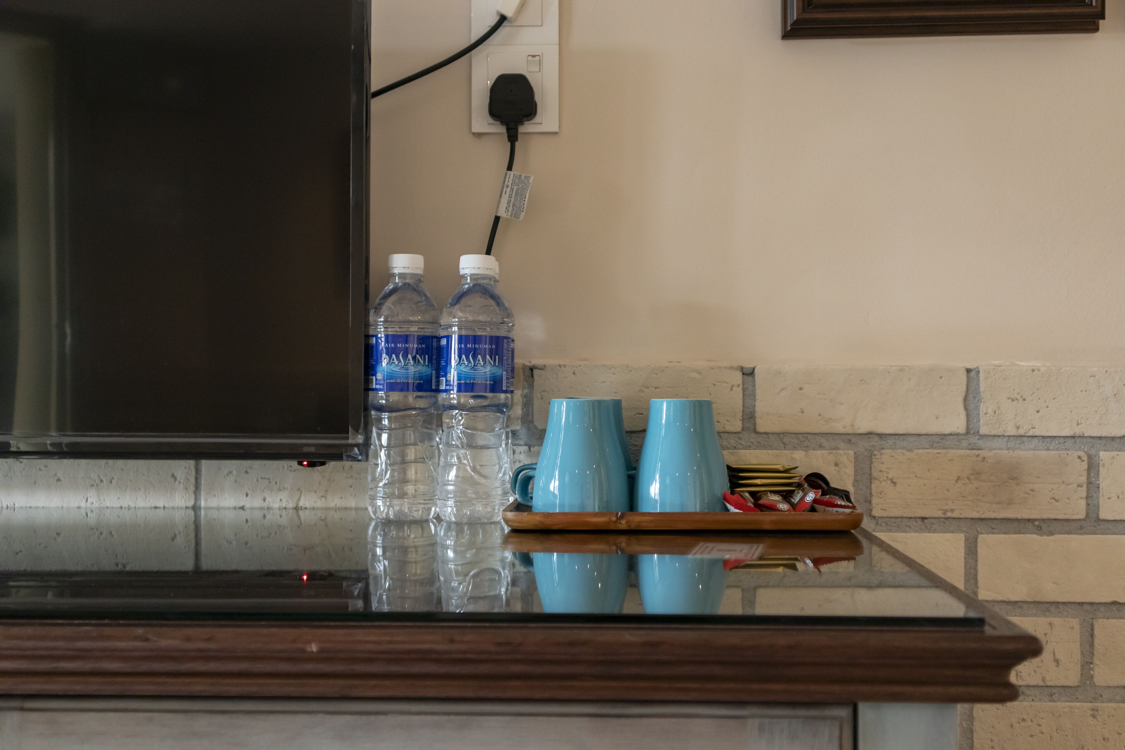 A kitchen counter with two water bottles, two blue mugs, and a tray with utensils.