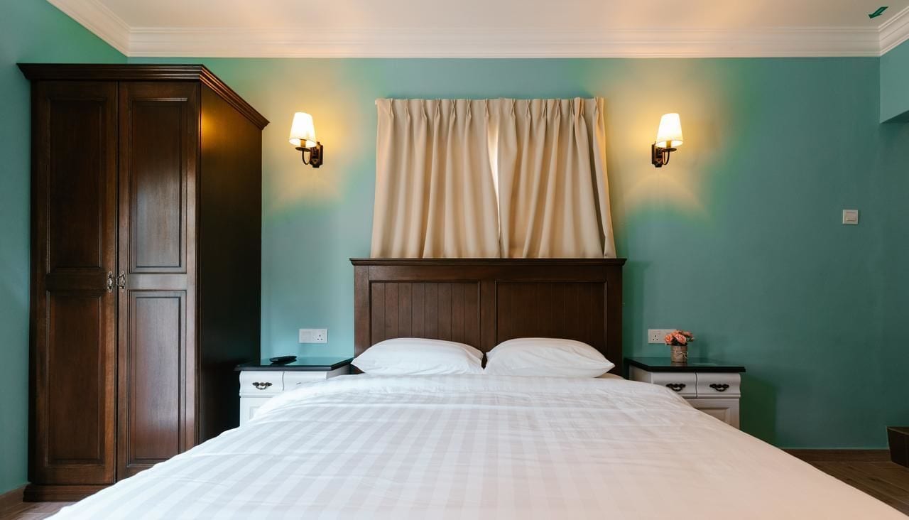 Un dormitorio con una cama grande, dos mesitas de noche, un armario y una ventana con cortinas.