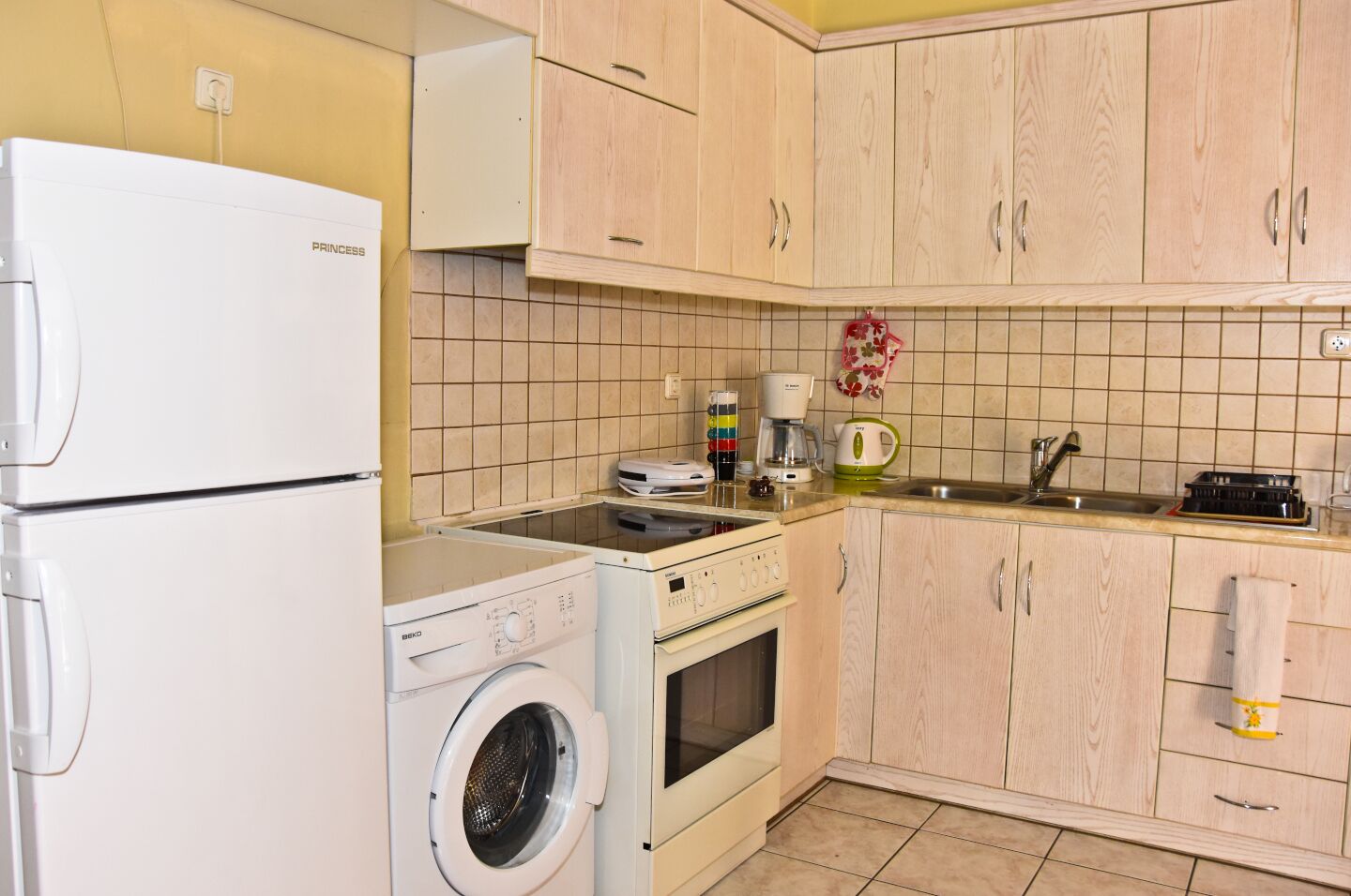A compact kitchen with a washing machine, a coffee maker, and a toaster.