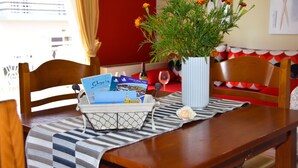 A dining table with a vase of flowers, a basket of brochures, and a wine glass. - Steps from the beach, Near city centre,Angela apartment (Chania)
