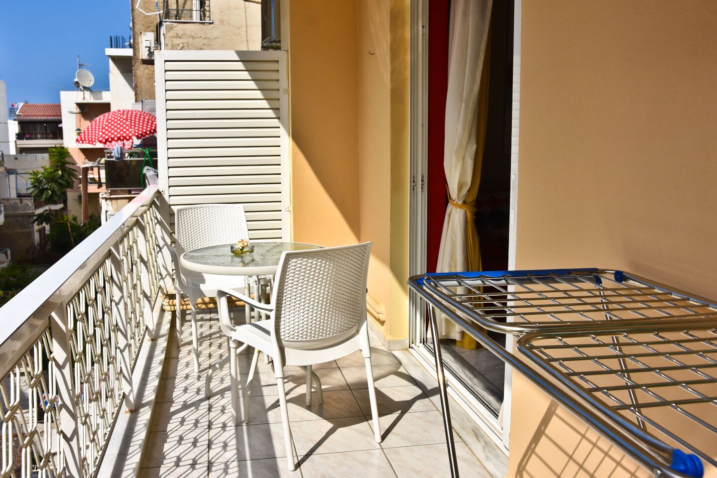 Un balcón con una mesa y sillas, un tendedero y vistas a edificios cercanos.