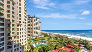 A high-rise hotel with multiple balconies overlooking a beach and ocean.