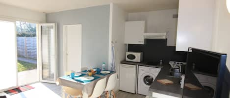 A compact kitchen with a dining area, a washing machine, and a microwave.