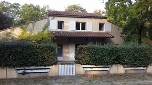 Ein zweigeschossiges Haus mit einem Ziegeldach, weißen Fensterläden und einer Satellitenschüssel.