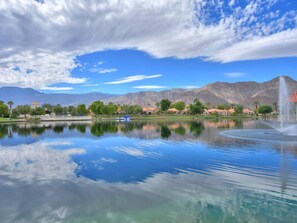 A serene lake with a fountain, surrounded by mountains and a clear sky. - 214 Vista de Nopal 2 bedroom (La Quinta)