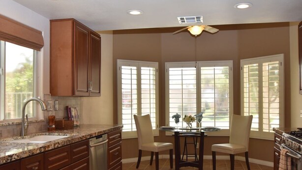 A kitchen with a granite countertop, stainless steel appliances, and a dining area with a round table and chairs.