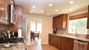 A modern kitchen with granite countertops, stainless steel appliances, and wooden cabinets.