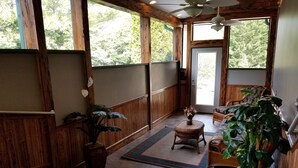 Une pièce spacieuse avec des lambris en bois, une grande fenêtre et un ventilateur de plafond.