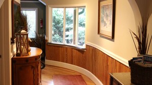 Une pièce avec un plancher en bois, un tapis rouge, une armoire en bois, une fenêtre donnant sur des arbres et un luminaire au plafond.