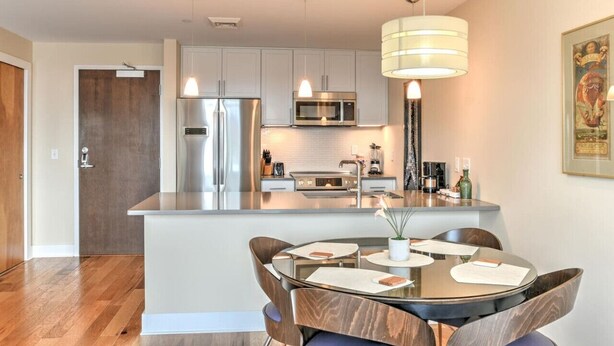 Una cocina moderna con una isla central, electrodomésticos de acero inoxidable y un comedor con una mesa redonda y sillas.