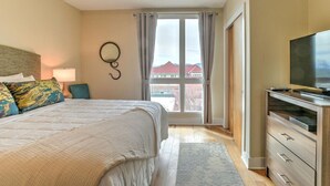 Habitación de hotel con una cama grande, televisión, cómoda y vistas a edificios a través de una ventana.