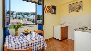 A small kitchen with a dining area, a view of the city, and a painting on the wall.