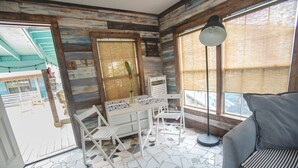 Une pièce avec un mur en bois, un bureau avec des chaises, un sol recouvert de carreaux de mosaïque et une fenêtre donnant sur un paysage.