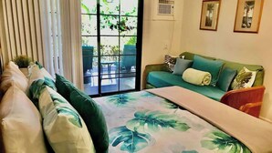 Een slaapkamer met een bed, een groene bank en een schuifdeur naar een terras.