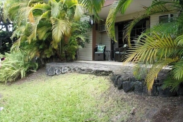 Relax in a serene tropical setting surrounded by lush greenery and a covered seating area.
