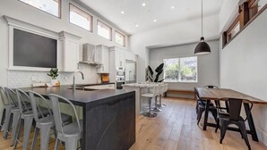 Une cuisine moderne dotée d’un îlot central, de tabourets de bar et d’une table à manger avec des chaises.