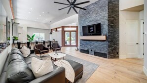 Un vaste salon doté d’une cheminée moderne, d’un canapé en cuir et d’un ventilateur de plafond.