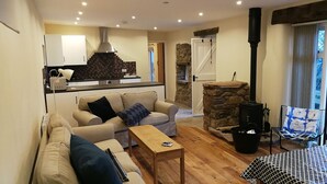 A cozy living room with a sofa, a coffee table, and a stone fireplace.