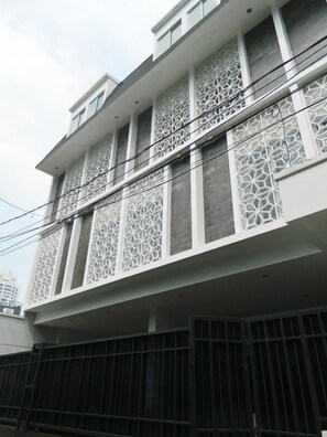 Un bâtiment à l’architecture moderne, doté d’un balcon orné d’un délicat treillis blanc et d’une clôture en métal foncé à sa base.