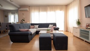 A modern living room with a sectional sofa, a coffee table, and a dining area in the background. - Holiday House App Grace with pool and view in Klis (Klis)