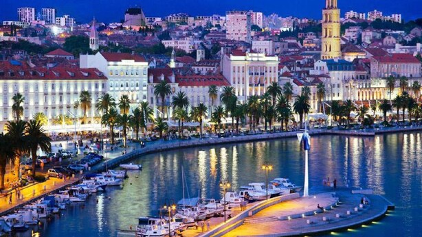 A marina with boats docked, a waterfront promenade, and a prominent tower in the background. - Holiday House App Grace with pool and view in Klis (Klis)