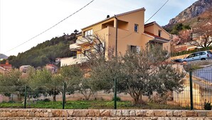 A two-story building with a stone wall in the foreground. - Holiday House App Grace with pool and view in Klis (Klis)