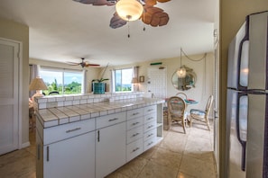 A kitchen with a large island, white cabinets, and a ceiling fan. - Great Sunset, Ocean and Mountain Views (Princeville)