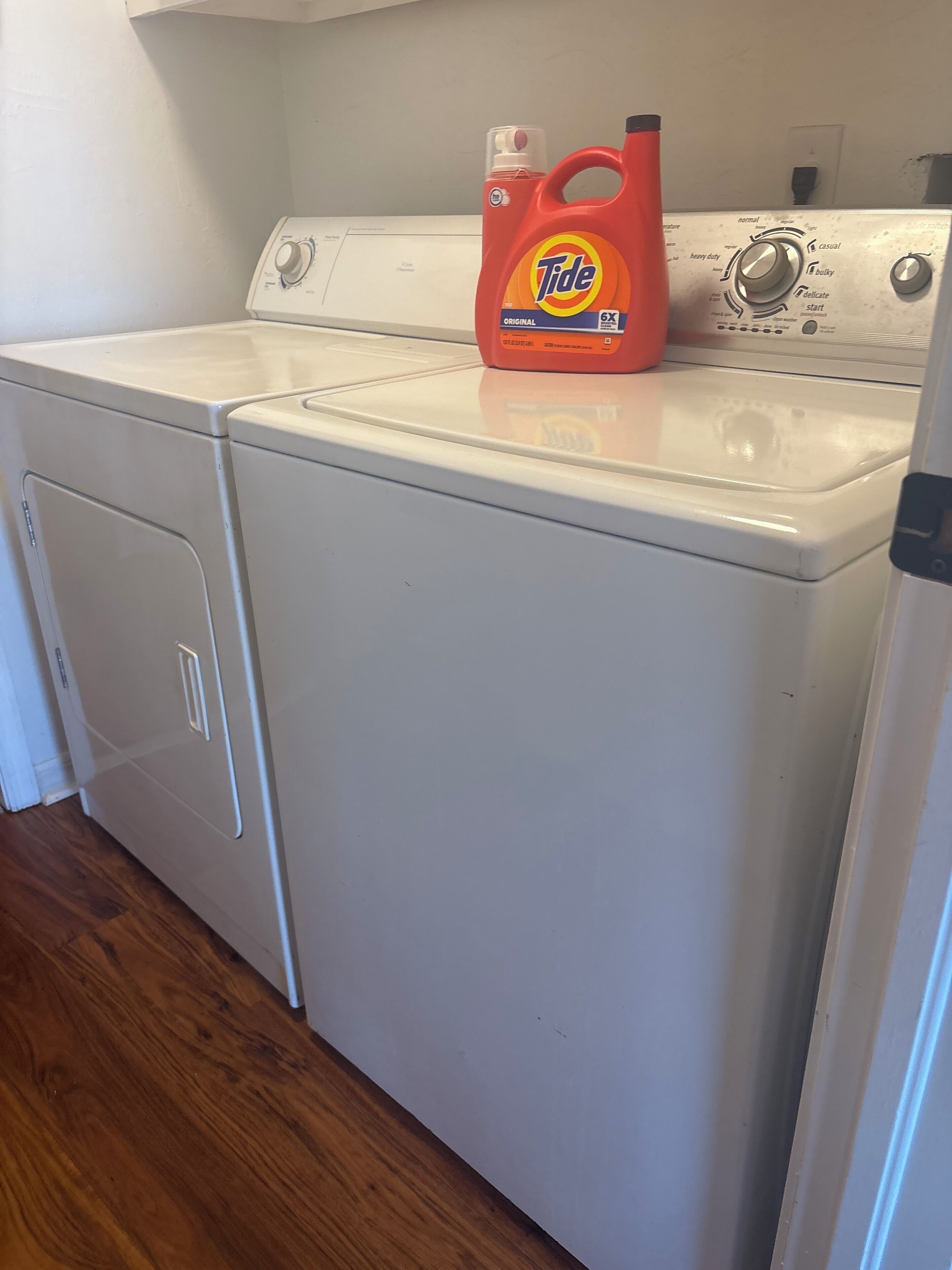 Une buanderie équipée de deux lave-linge à chargement frontal blancs, et une bouteille de lessive Tide posée sur le lave-linge de droite.