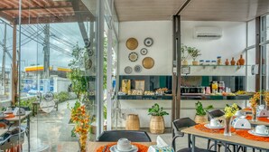 Un comedor moderno con paredes de vidrio, vista a una gasolinera y una cocina al fondo.