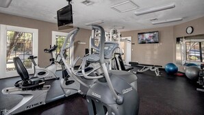 Un gimnasio con máquinas de cardio, equipo de pesas y pelotas de ejercicio.