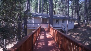 A wooden deck leading to a cabin surrounded by trees. - Spacious, bright, cozy, single floor home nestled in pine trees (Groveland)