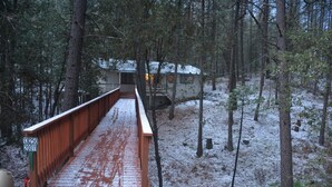 A wooden bridge leading to a cabin in a snowy forest. - Spacious, bright, cozy, single floor home nestled in pine trees (Groveland)