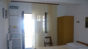 Ein Schlafzimmer mit einem Bett, einem Kleiderschrank, einem kleinen Tisch und einem Kühlschrank.