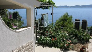 Ein Balkon mit Seeblick, eine Wäscheleine mit Wäsche und ein Garten mit verschiedenen Pflanzen.
