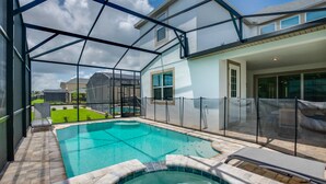 Une piscine dotée d’une structure en verre, un jacuzzi et un espace patio avec des chaises longues.