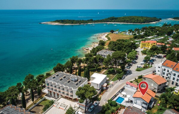 An aerial view of a coastal area with a hotel, clear turquoise waters, and a small island in the distance. - Stunning home in Banjole (Banjole)
