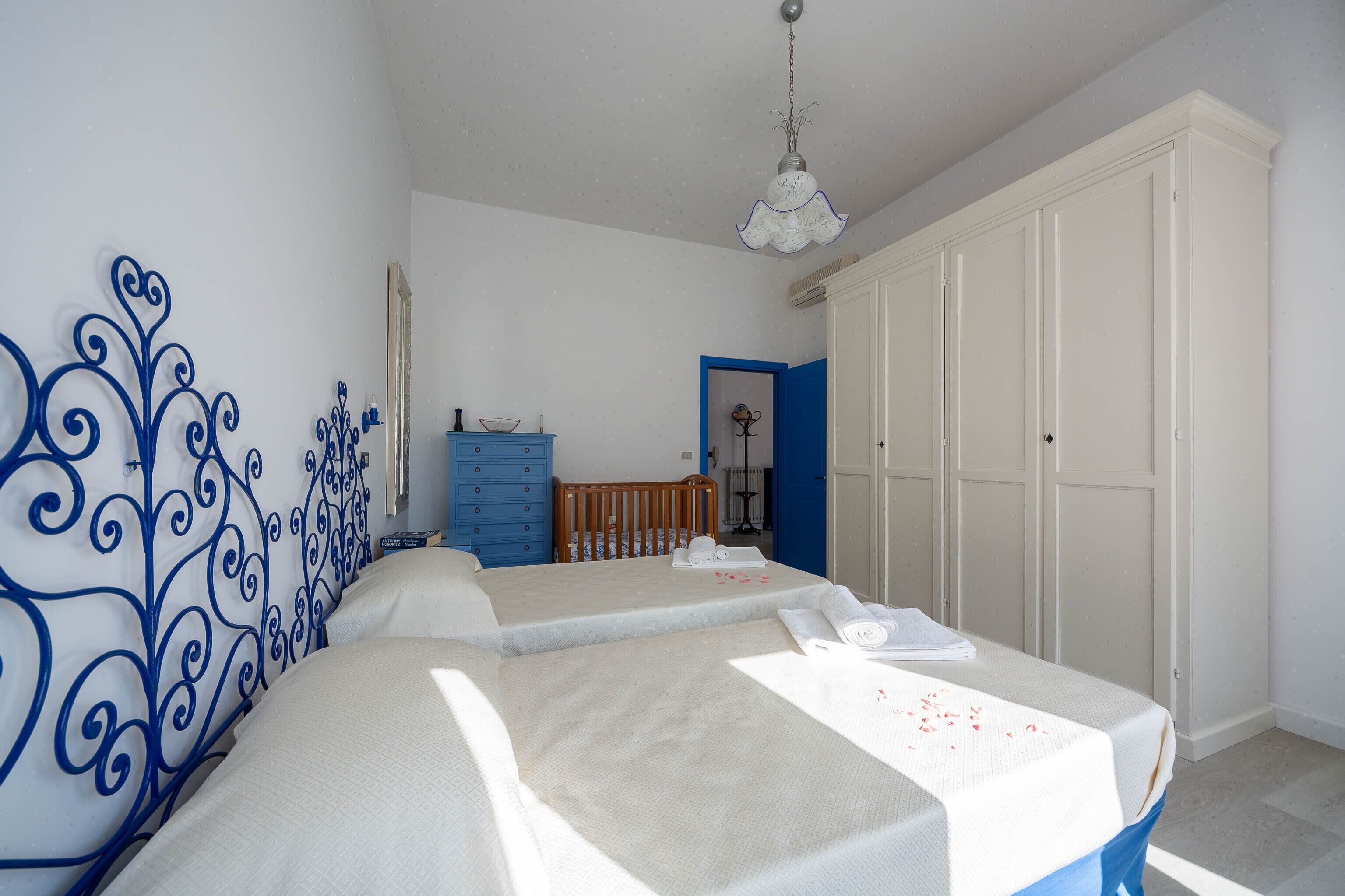 Un dormitorio con dos camas, un armario, un aparador y una cuna.