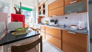 A modern kitchen with wooden cabinets, a black countertop, and a red appliance. - Casa Roberta (Maiori)