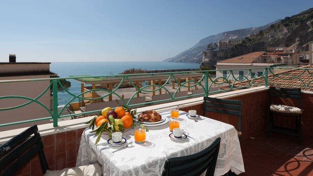 A terrace with a table set for breakfast, overlooking a coastal view. - Casa Roberta (Maiori)
