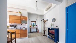 A modern kitchen with wooden cabinets, a dining area with a chair, and a blue door. - Casa Roberta (Maiori)