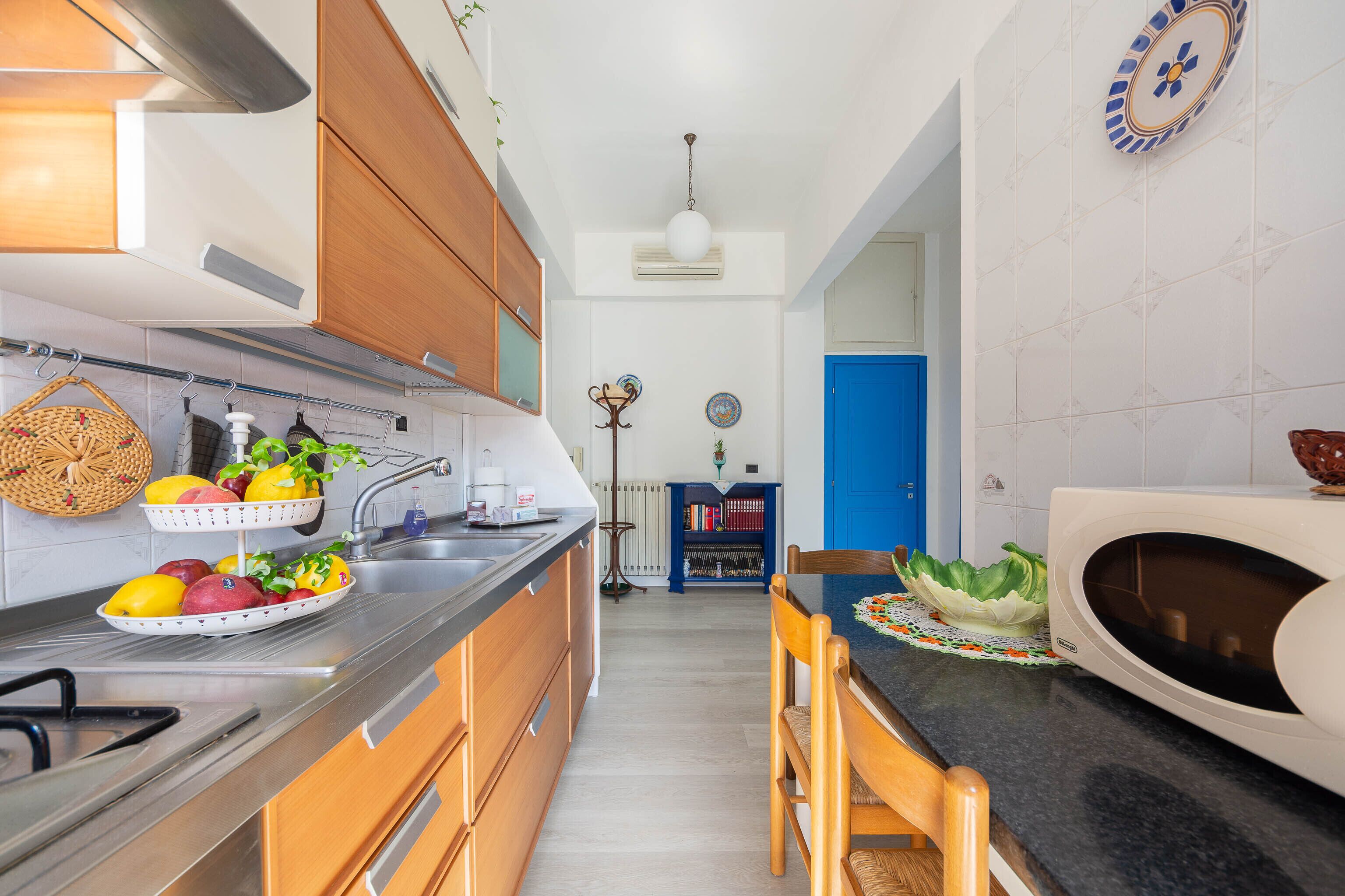 A modern kitchen with wooden cabinets, a black countertop, and a microwave.