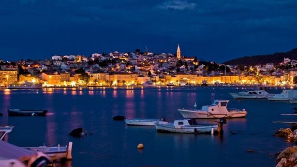 A coastal town at dusk with boats docked in the harbor and buildings illuminated in the background. - Apartment in Mali Lošinj with Balcony, Air condition, WIFI (72-1) (Mali Lošinj)