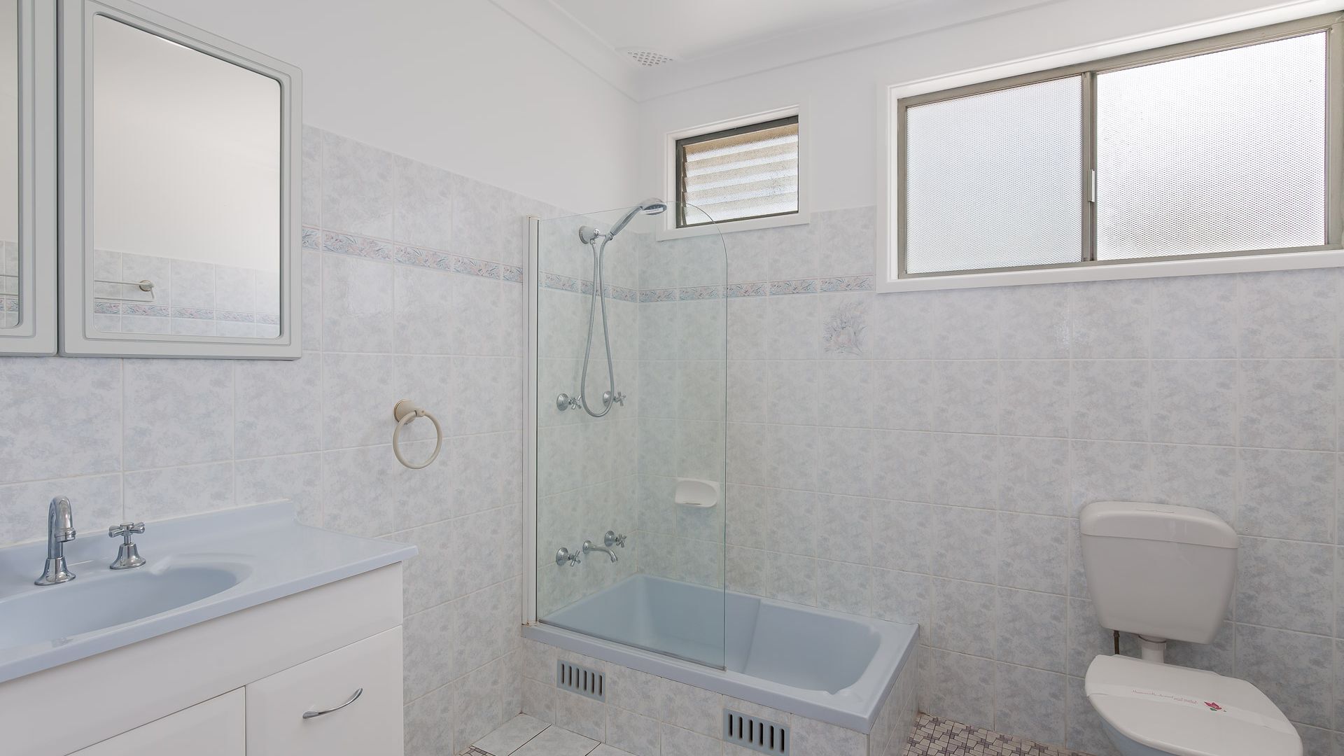 A modern bathroom with a glass-enclosed shower, a bathtub, a toilet, and a vanity with a sink.
