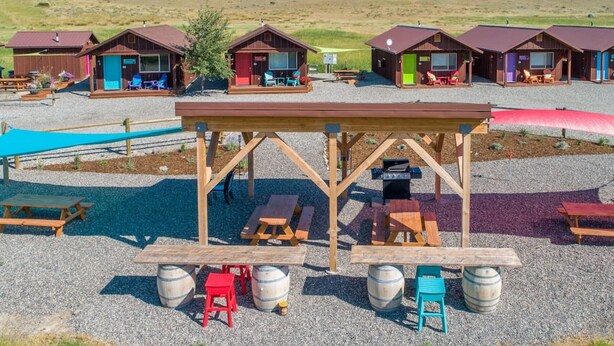 A campground with wooden cabins, picnic tables, and barbecue grills. - Cabin 5 · Emigrant Cabins #5 - Affordable Tiny Cabin in MT (Emigrant)
