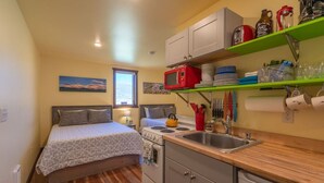 A compact room with a bed, kitchenette, and a window. - Cabin 5 · Emigrant Cabins #5 - Affordable Tiny Cabin in MT (Emigrant)