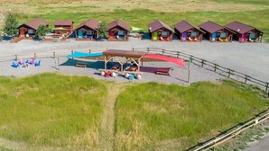 A row of cabins with a covered seating area and a gravel path leading to them. - Cabin 5 · Emigrant Cabins #5 - Affordable Tiny Cabin in MT (Emigrant)