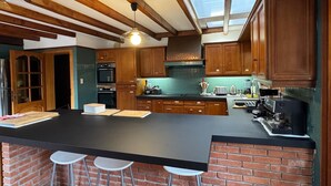 Een moderne keuken met houten kastjes, een zwart aanrecht en een accentmuur van baksteen.
