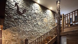 Una scala con parete in pietra e ringhiera in legno, che conduce a un livello inferiore.