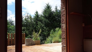 Een kamer met een houten terras dat uitkomt op een tuin.